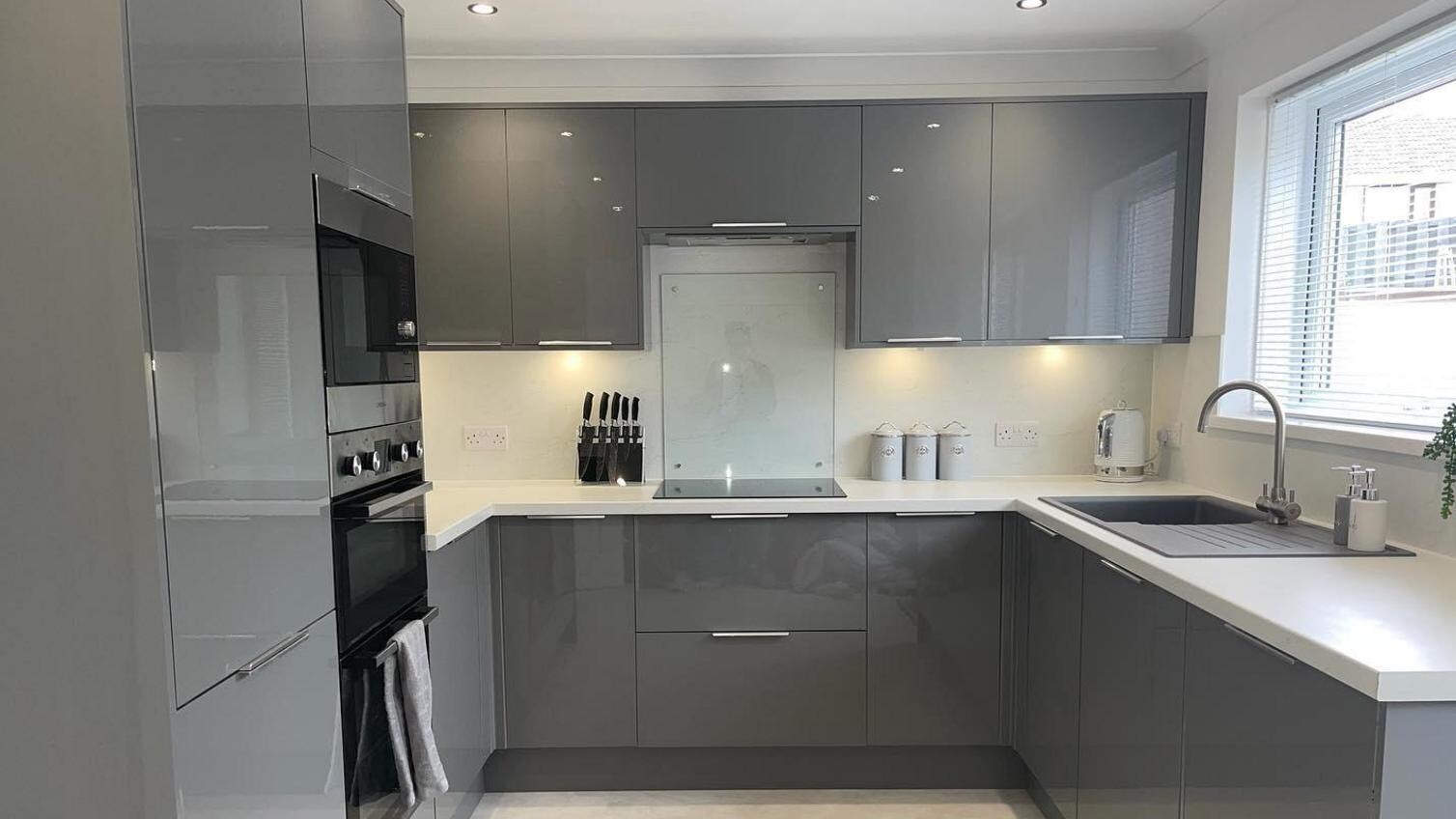 Grey gloss slab kitchen with stone-effect flooring and kitchen spotlights