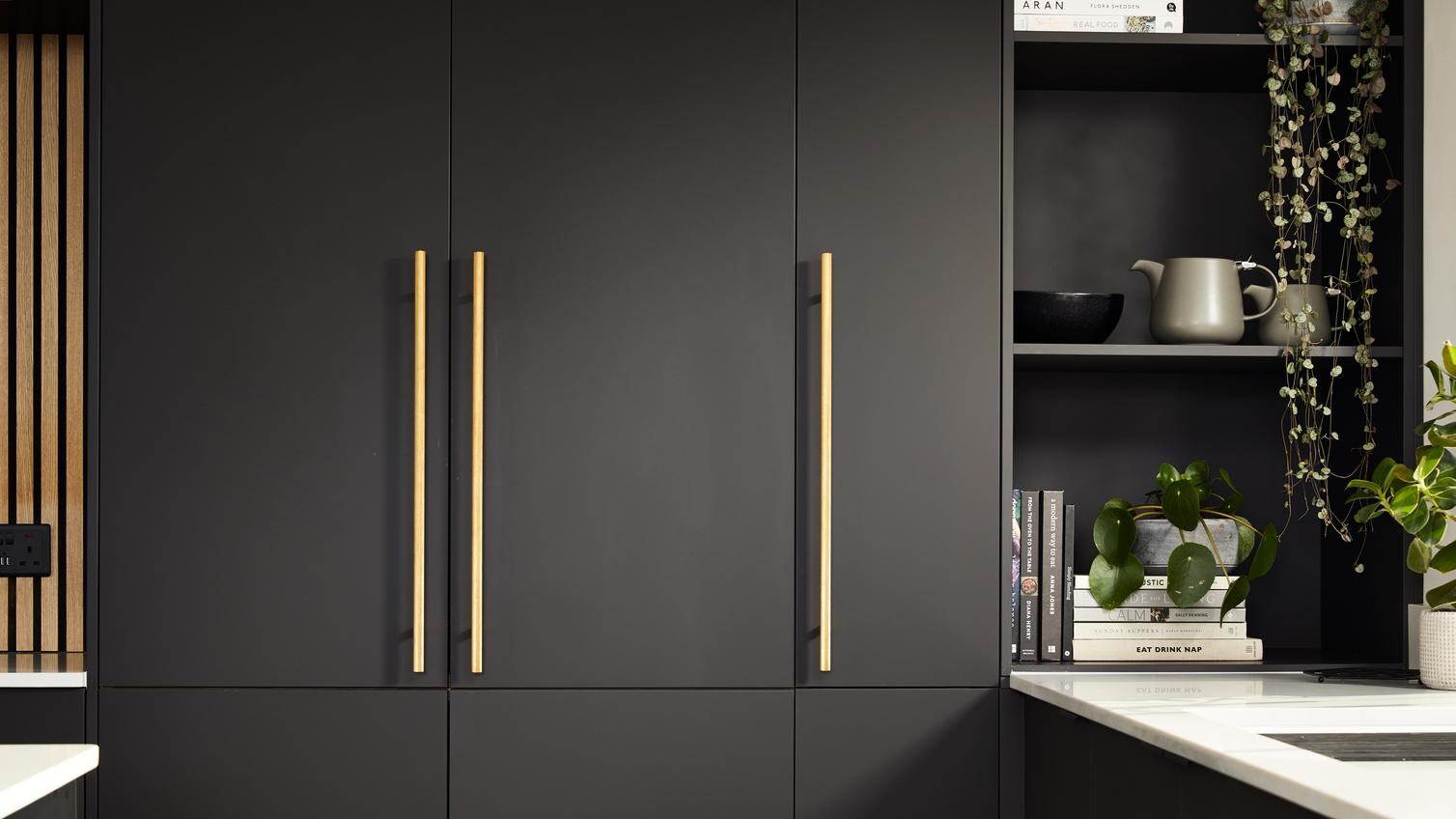 Howdens 2022 Kitchen Of The Year Winner's kitchen with rall cabinetry, brass handles, and open shelving.