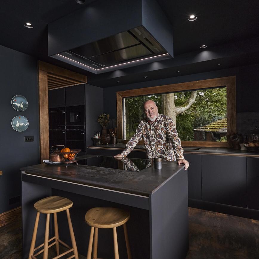 Comedian and musician Bill Bailey stood in his kitchen and smiling