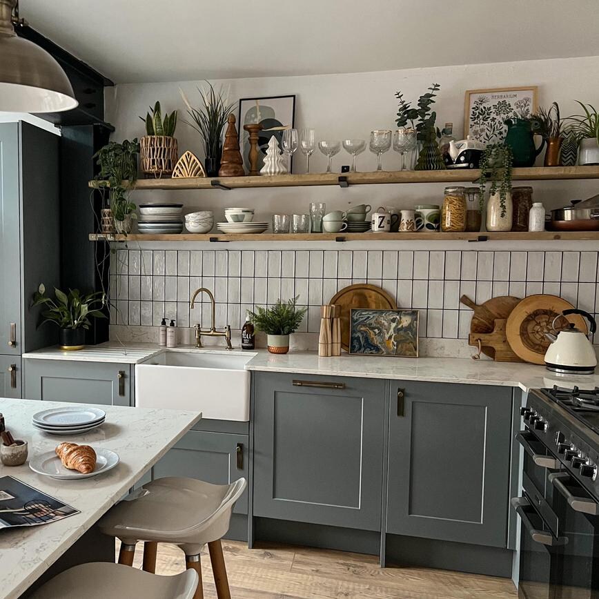 Dusk blue shaker kitchen with an island, white quartz worktop, open wood shelving, and kitchen accessories.