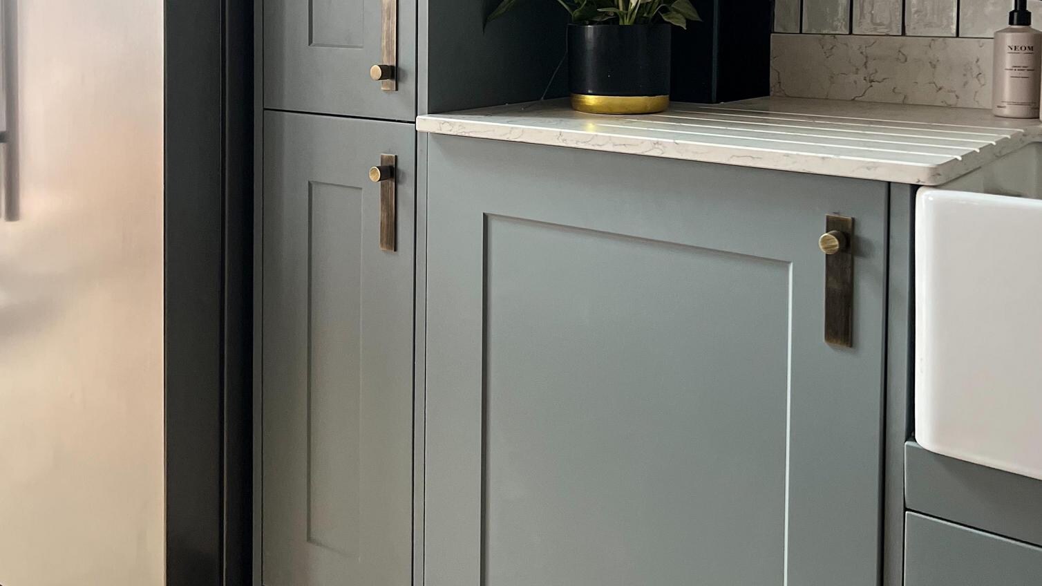 Dusk blue shaker wall cabinets with a tower unit, white ceramic sink, white quartz worktop and American fridge freezer.