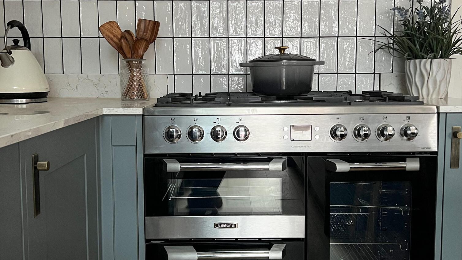 Dusk blue shaker kitchen idea with a black and silver range cooker, white subway tiles, and a silver chimney extractor fan.