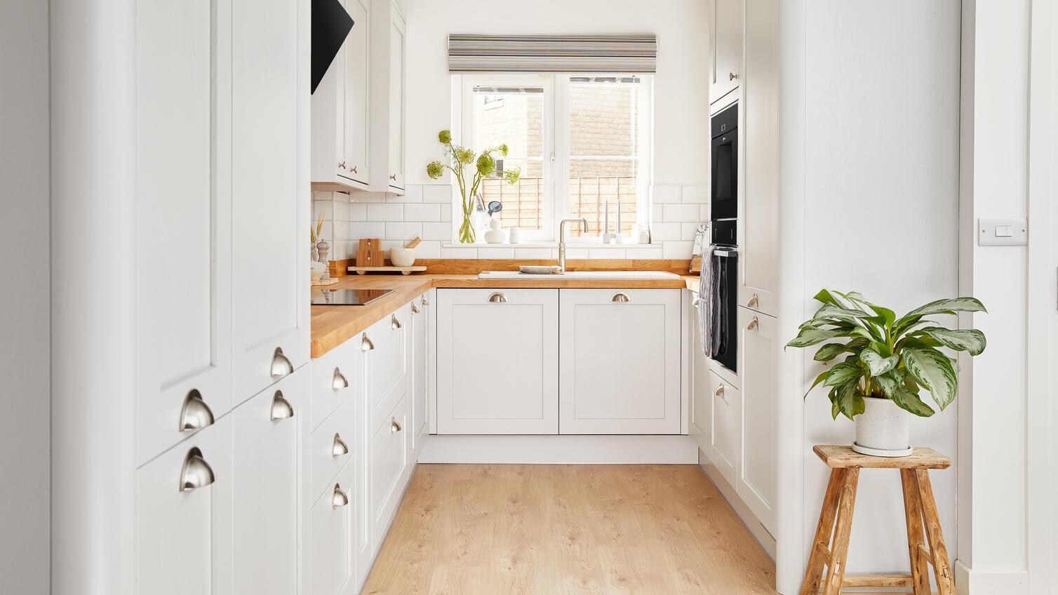 A wide shot of Ellen White's Howdens kitchen, with a pleasant plant and a bright window