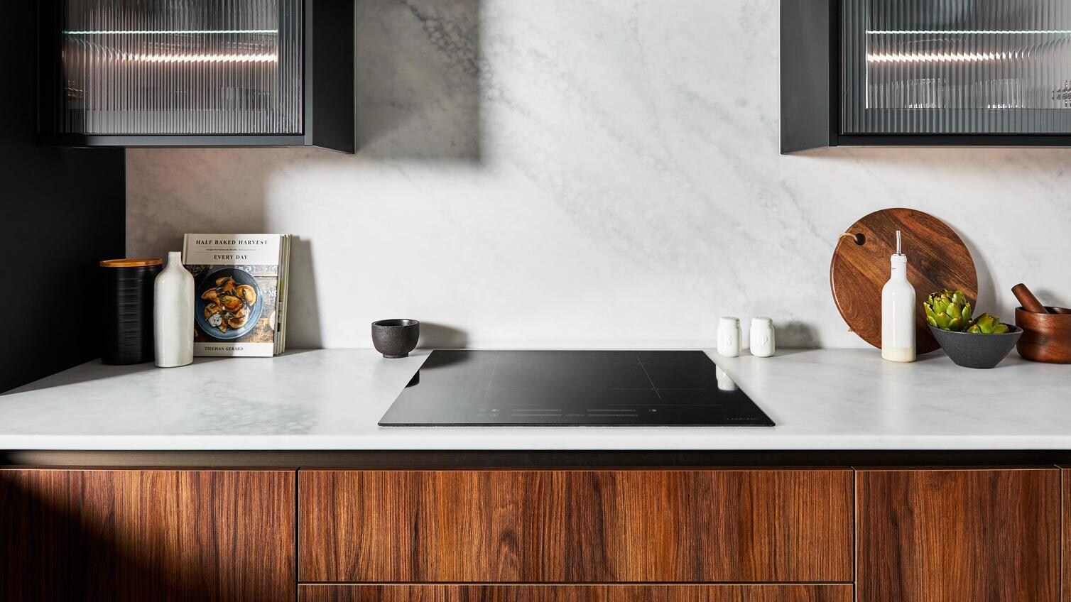 Modern kitchen featuring white, bespoke worktops, fluted glass wall units, and handleless cupboards with a walnut design.