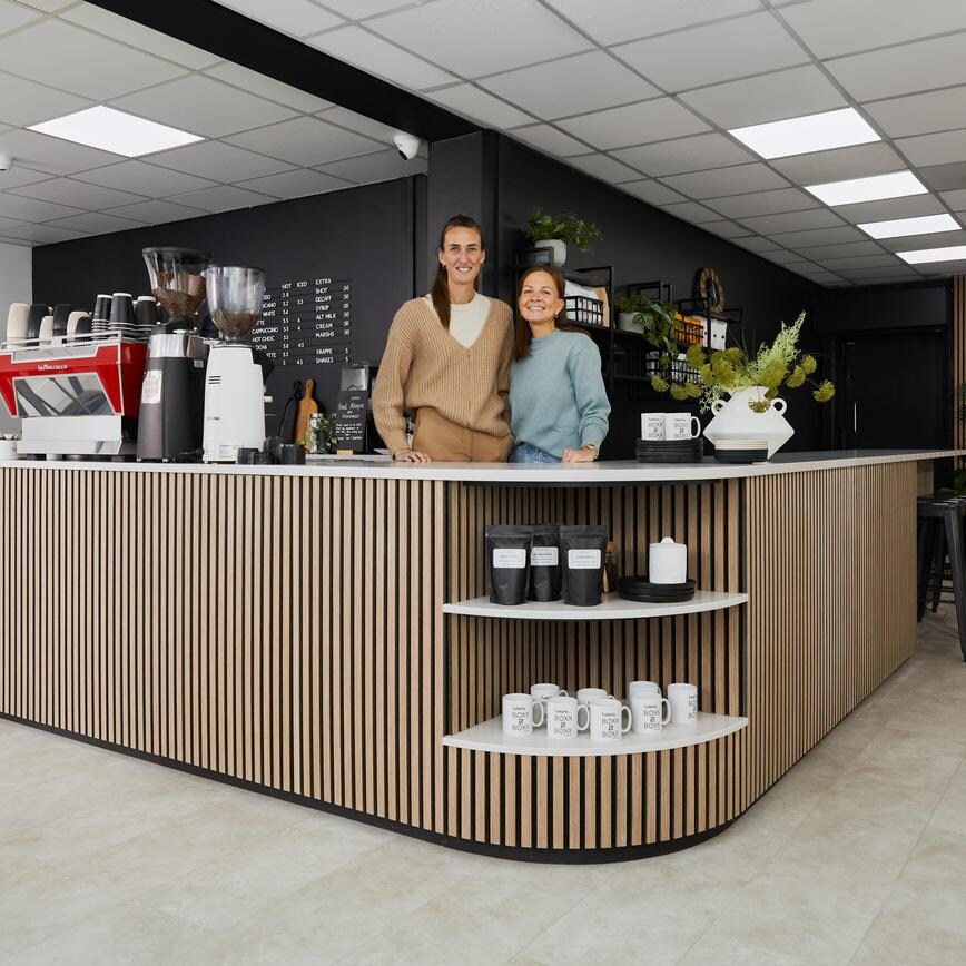 Jill Scott Cafe Kitchen Makeover with Jill and her fiancee standing behind a counter with oak wall panelling