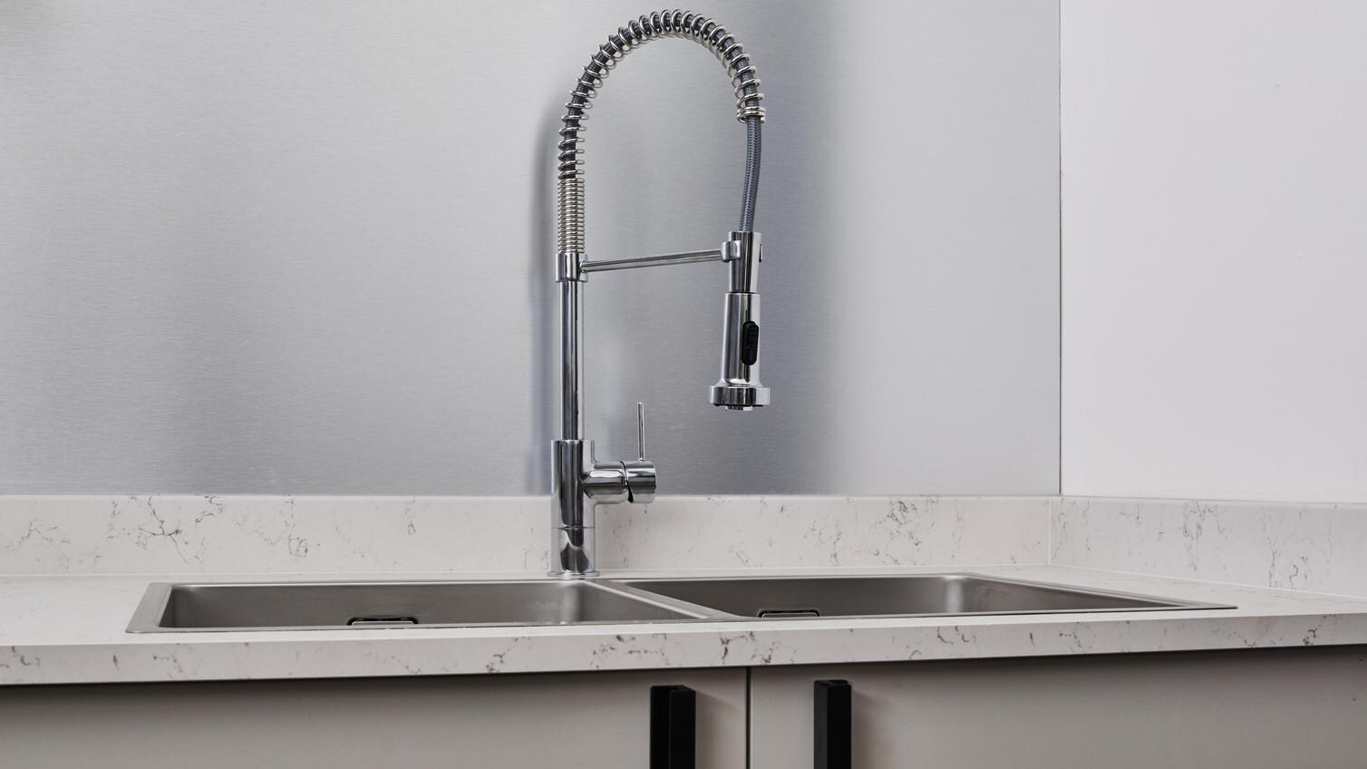 Jill Scott Cafe Kitchen Makeover with a chrome, pull-out tap and stainless-steel, double bowl sink fitted flush with a worktop.