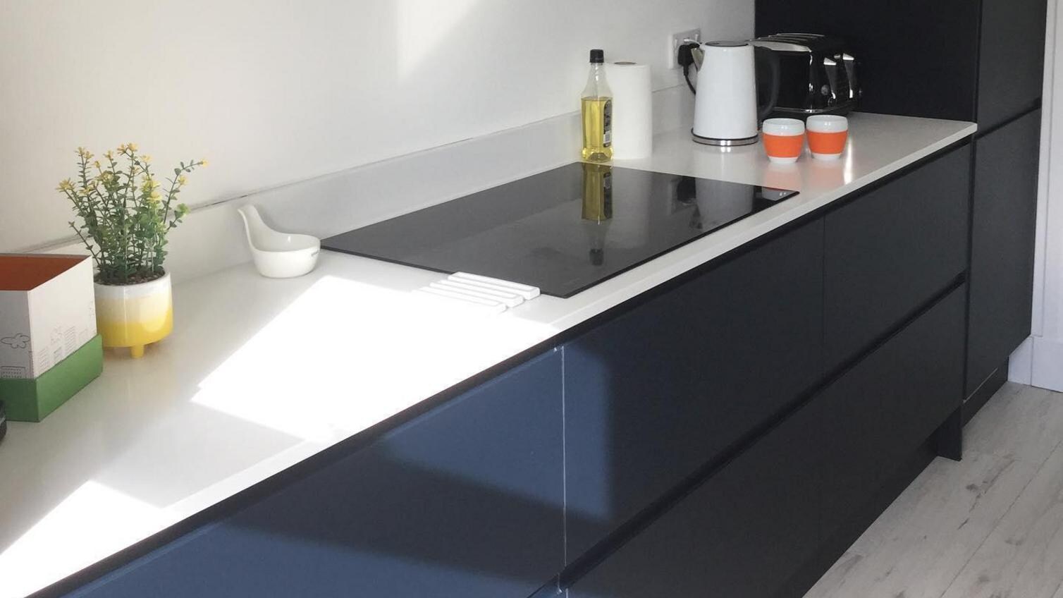 Super-matt navy integrated handle doors, double drawer cabinets, and a black induction hob for a simple blue kitchen idea.