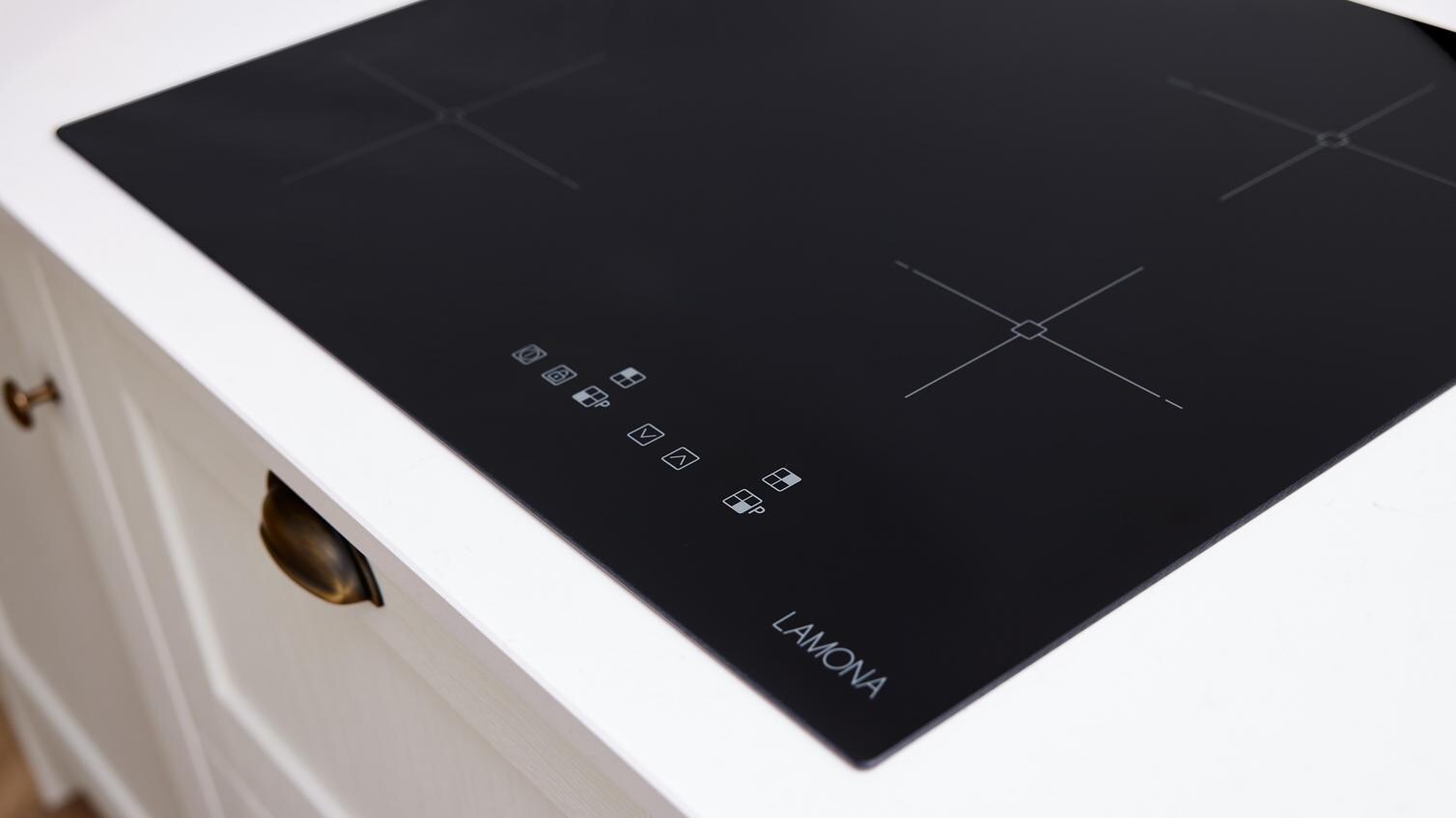 An induction hob built into the white laminate worktop of a Howdens Halesworth kitchen