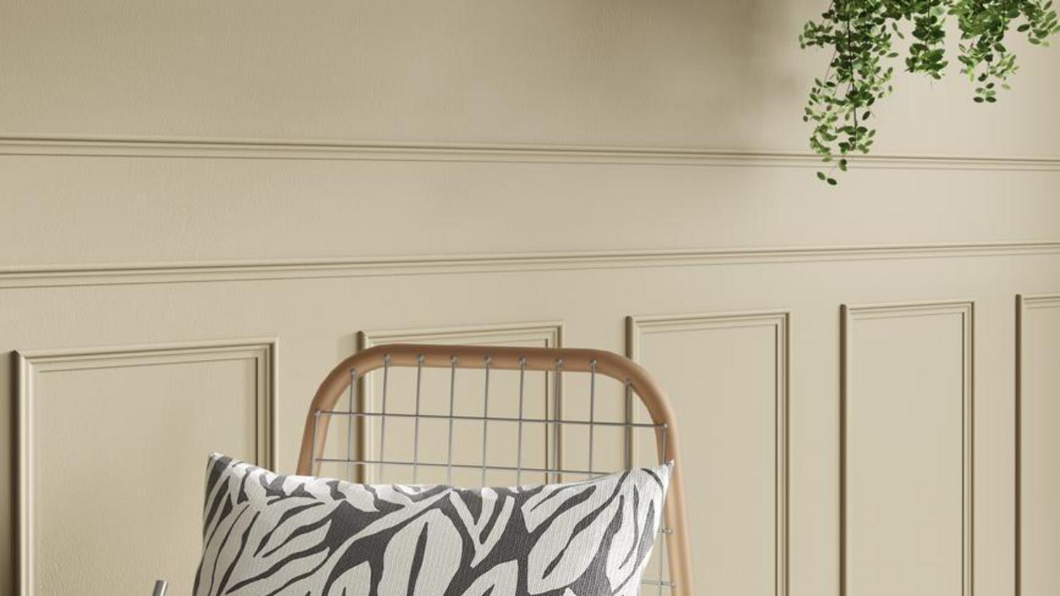 A chair and table in front of a wall, which has decorative mouldings for visual interest