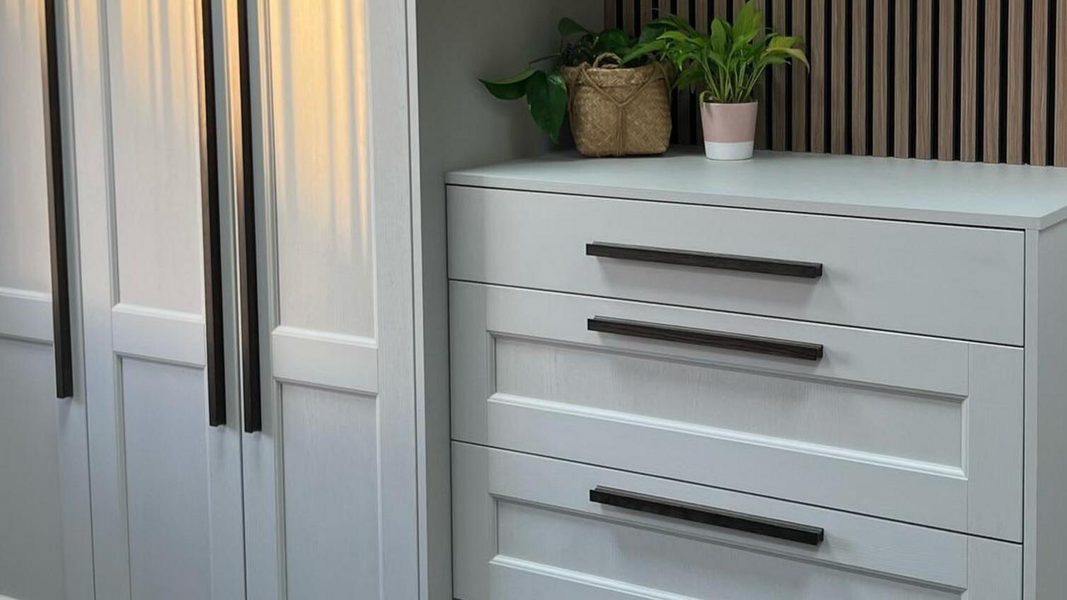 A white, fitted bedroom set from Howdens, with rich timber handles