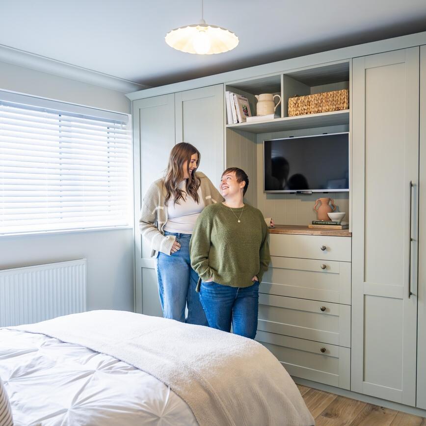 Rhiannon and Kayleigh stood in their Howdens bedroom, which is in a reed green colour from the Halesworth collection.