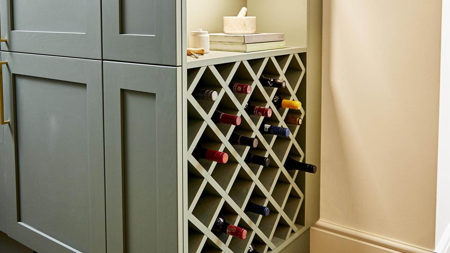 Sage green shaker kitchen design with built in cupboards on the side of unit, with accessories and a custom wine rack.