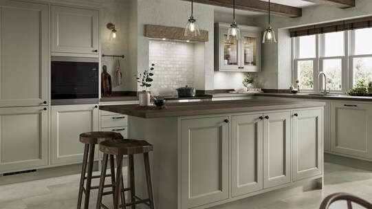 A sage-green in-frame shaker kitchen with an island. Has dark wood worktops, a range cooker, knob handles, and tile floors.