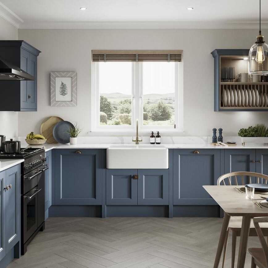 L- shape paintable kitchen with green shaker cupboards doors and beaded detail with white worktops and dark timber floors.