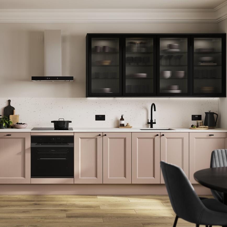 An antique-rose pink shaker kitchen in a single-wall layout. There are black glass wall cabinets and single-plank flooring.
