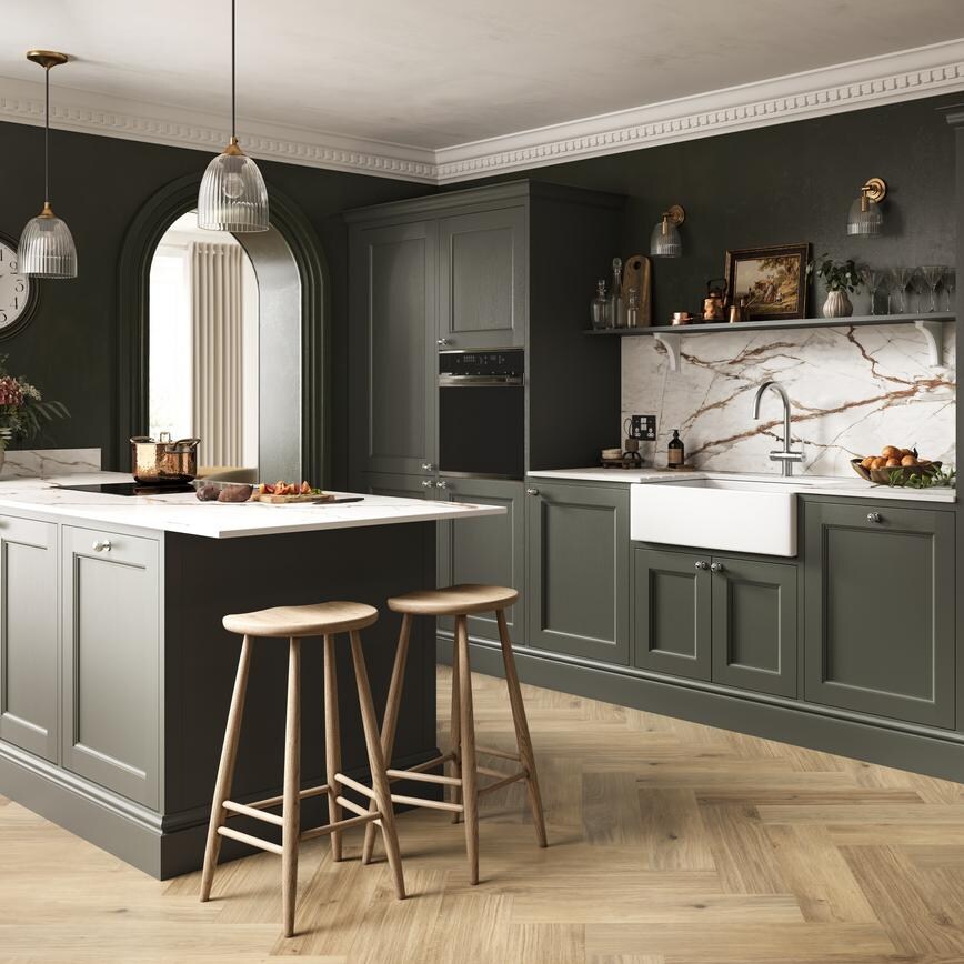 A dark-green kitchen with shaker doors in a single wall layout. It is styled with chevron timber flooring and white worktop.