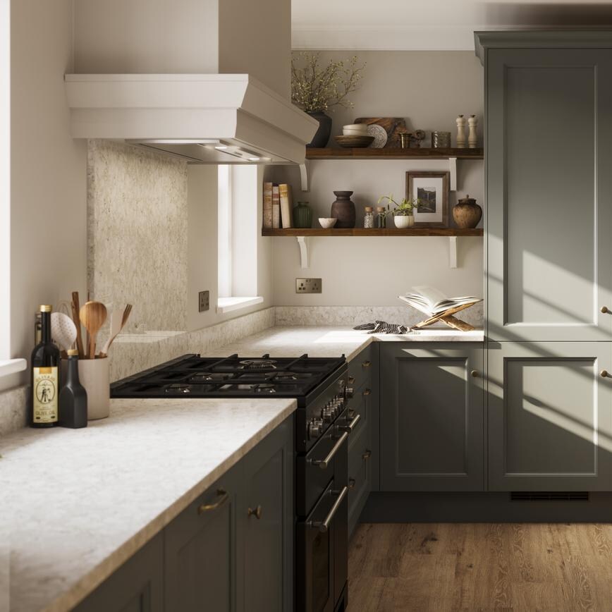 A green kitchen with shaker doors in an island layout. It has beige worktops, dark timber shelving, and plank flooring.