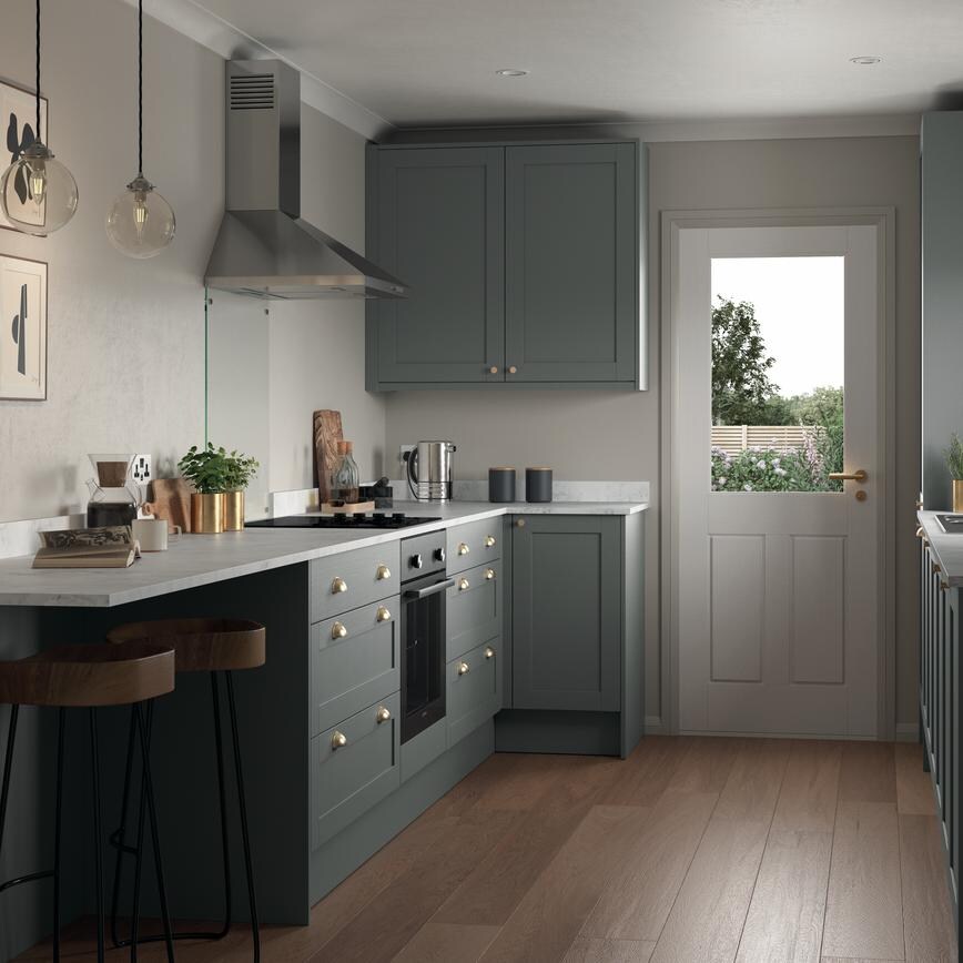 Compact grey kitchen in a galley layout. Features shaker doors, white worktops, and brass cup handles for a stately look