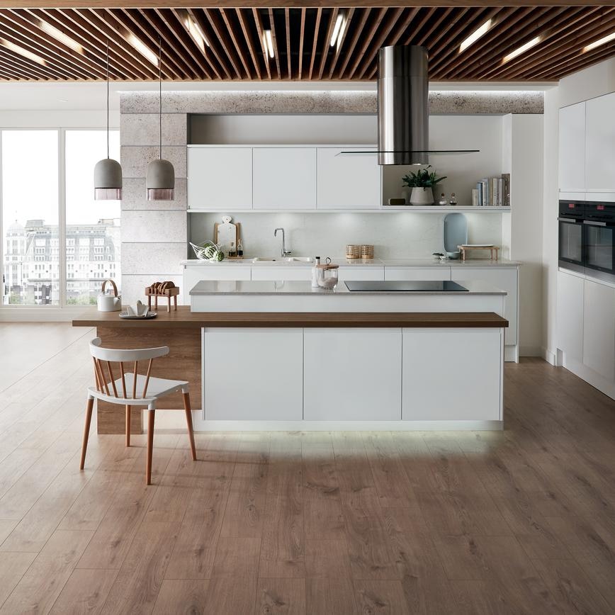 An open-plan Scandi white kitchen idea with super-matt handleless doors, a ceiling-mounted cooker hood, and a white sink.
