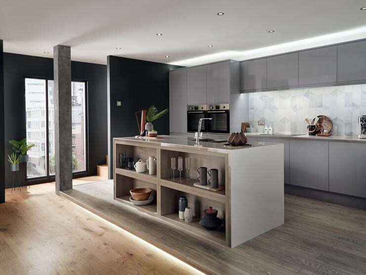 Slate grey modern handleless gloss kitchen in an apartment setting including kitchen island incorporating exposed shelving.