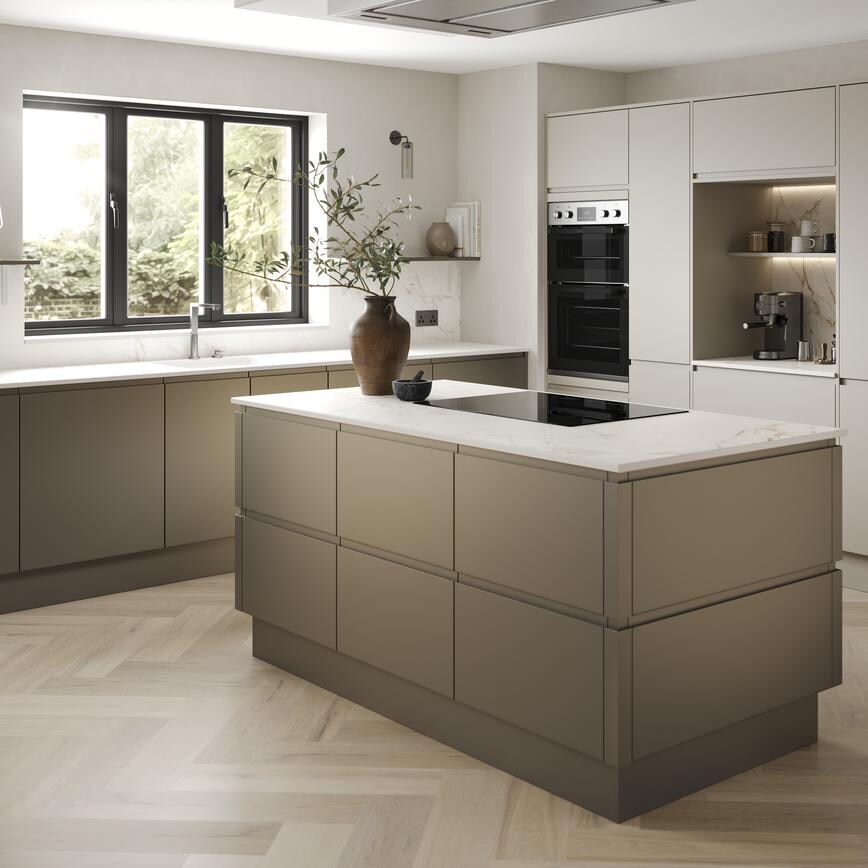 A handleless, bronze kitchen in an L-shaped, island layout. It has white worktops, chevron flooring, and an induction hob.