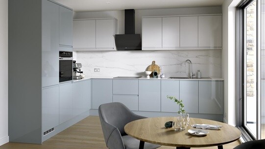 A blue kitchen from  Clerkenwell Mist, in an l-shaped layout. It has a gloss finish, white wall cabinets & marble backboard.