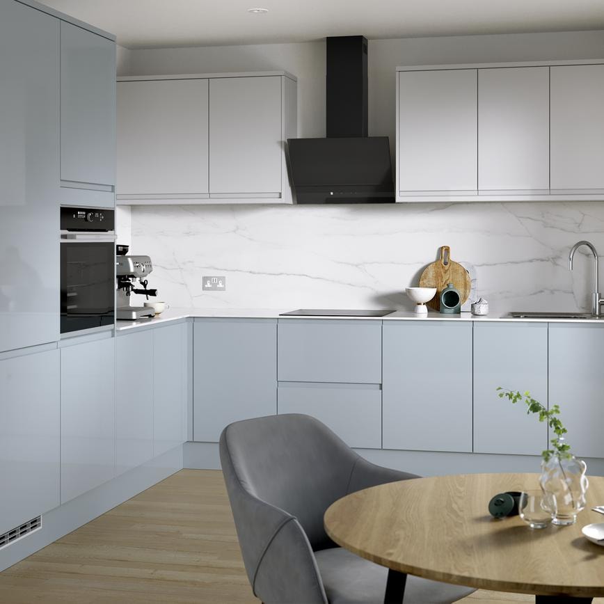 A blue kitchen from  Clerkenwell Mist, in an l-shaped layout. It has a gloss finish, white wall cabinets & marble backboard.