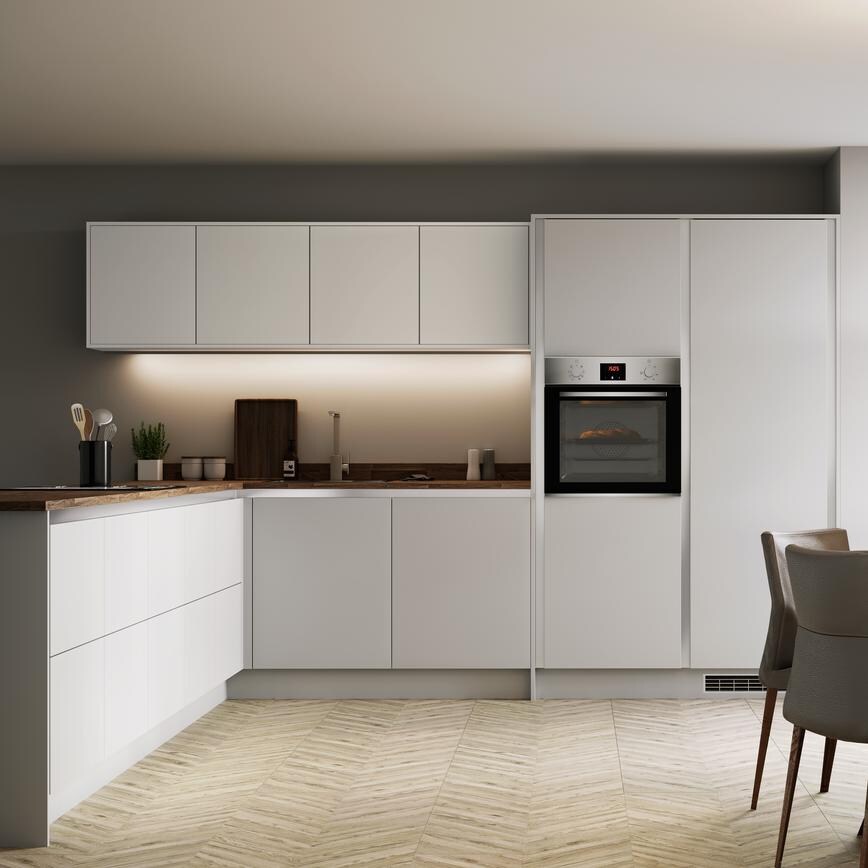 L shape dove grey handleless kitchen with single built in oven and round dining table overlooking mature garden.