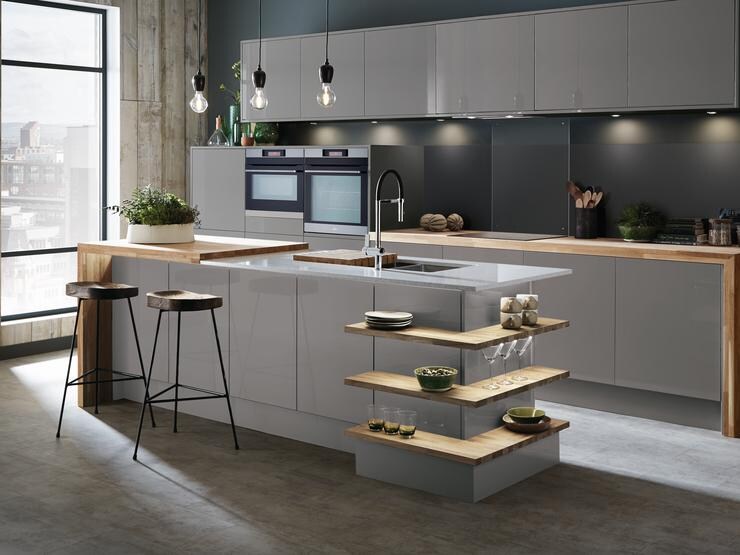 Slate grey gloss kitchen with island unit incorporating wrap around open shelves and breakfast bar with mirror chip worktop.