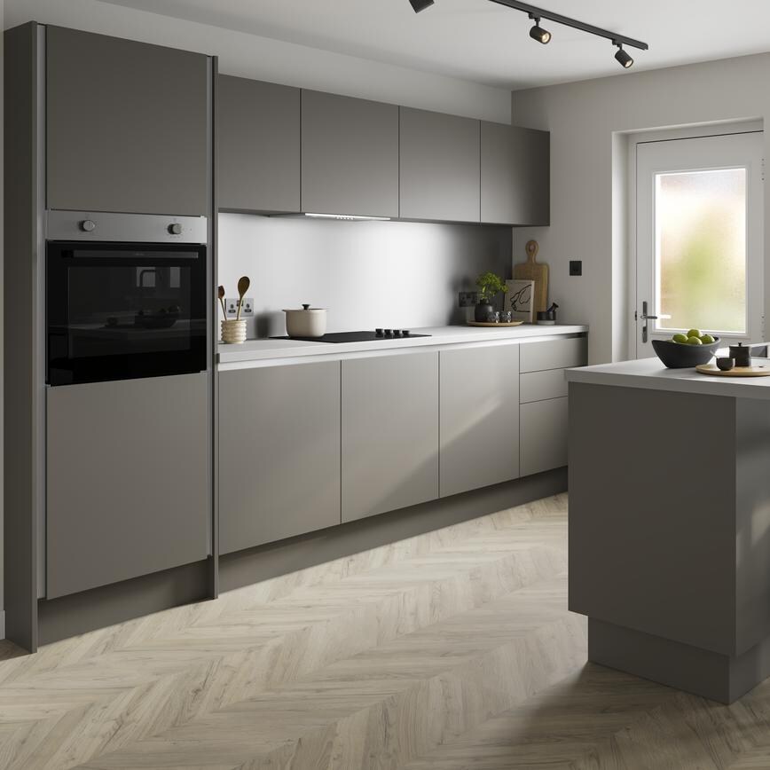An l-shaped kitchen layout with green cabinets white marble-effect worktop, and pale wood flooring.