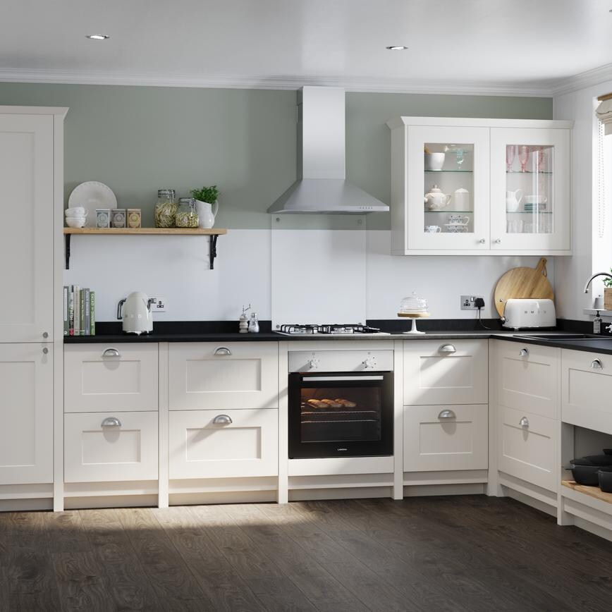 Classic cream shaker kitchen idea with ivory shaker doors in an L-shaped layout. Has silver cup handles and a built-in oven.