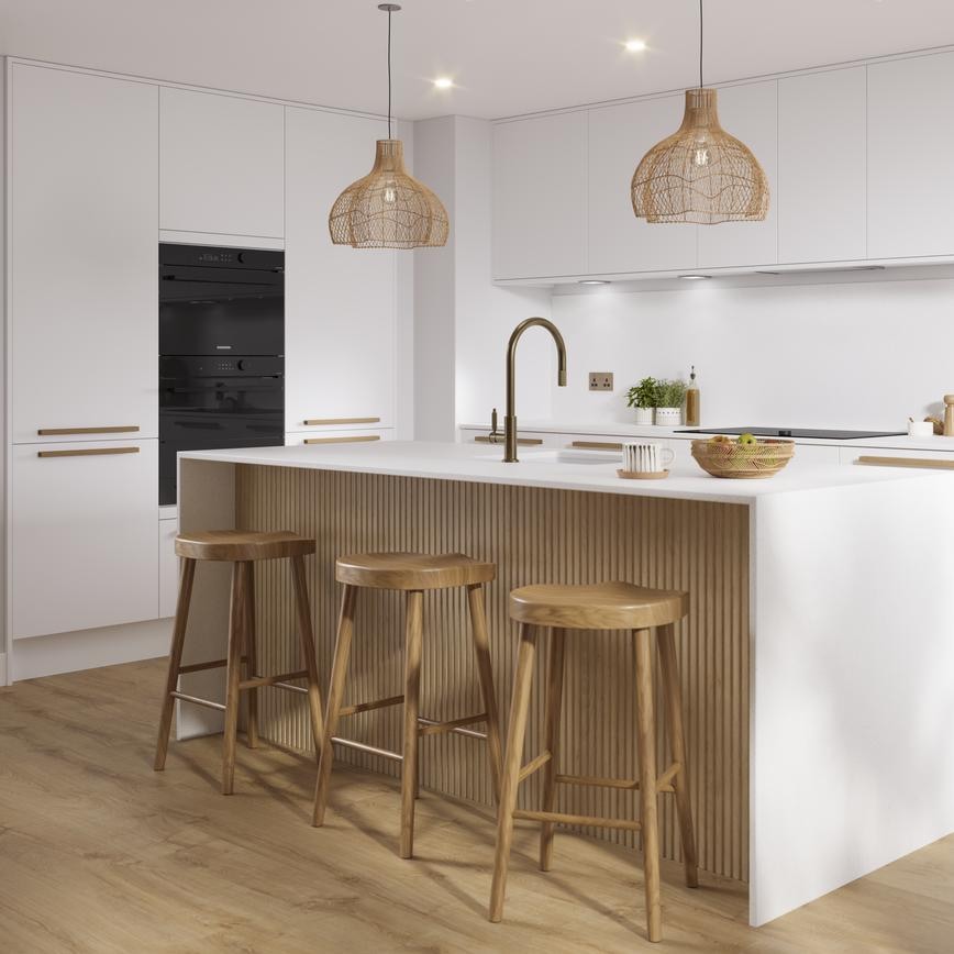 A matt white kitchen in an L-shape with island & brass accessories. The island has reeded oak panels with matching flooring.