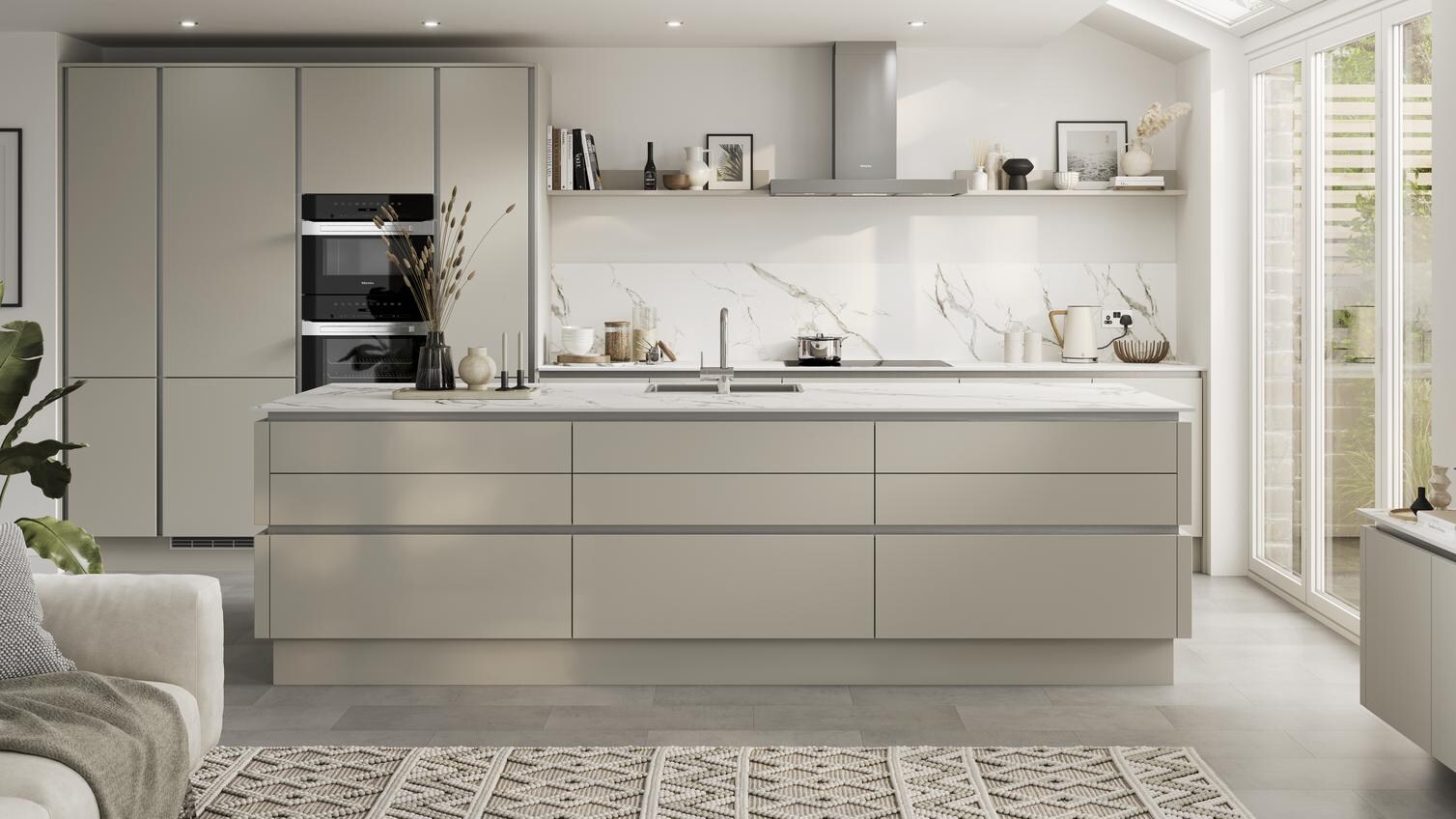 Neutral slab doors with a super-matt finish in an island layout. Has handleless units and silver trims for a modern look.