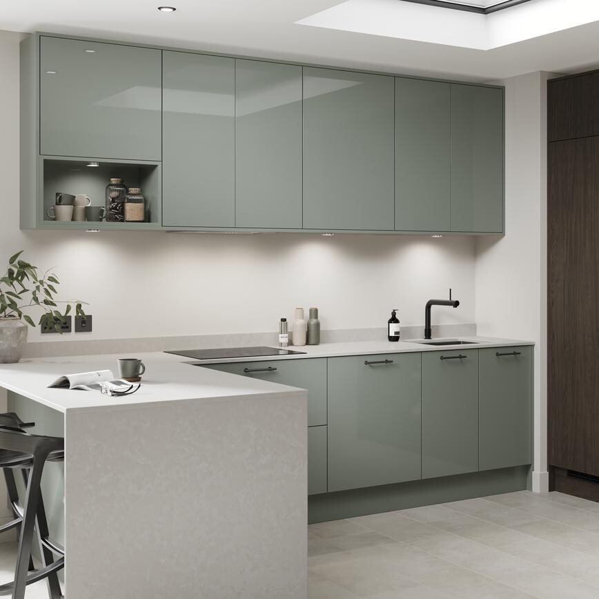 A peninsula kitchen in a gloss reed green finish. It has stone tiled flooring and larder units in a textured walnut effect.
