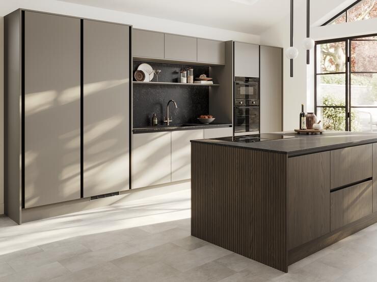 A sand grey kitchen with a slab design. It has a single wall layout with island. Black worktops and profiles also feature.