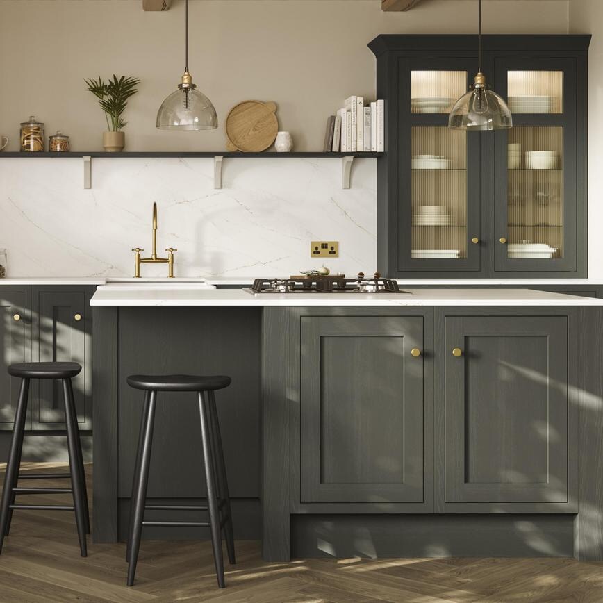 A green shaker kitchen from Ilfracombe Ash Green. It has a kitchen island, glass cabinets, and marble-style worktops.