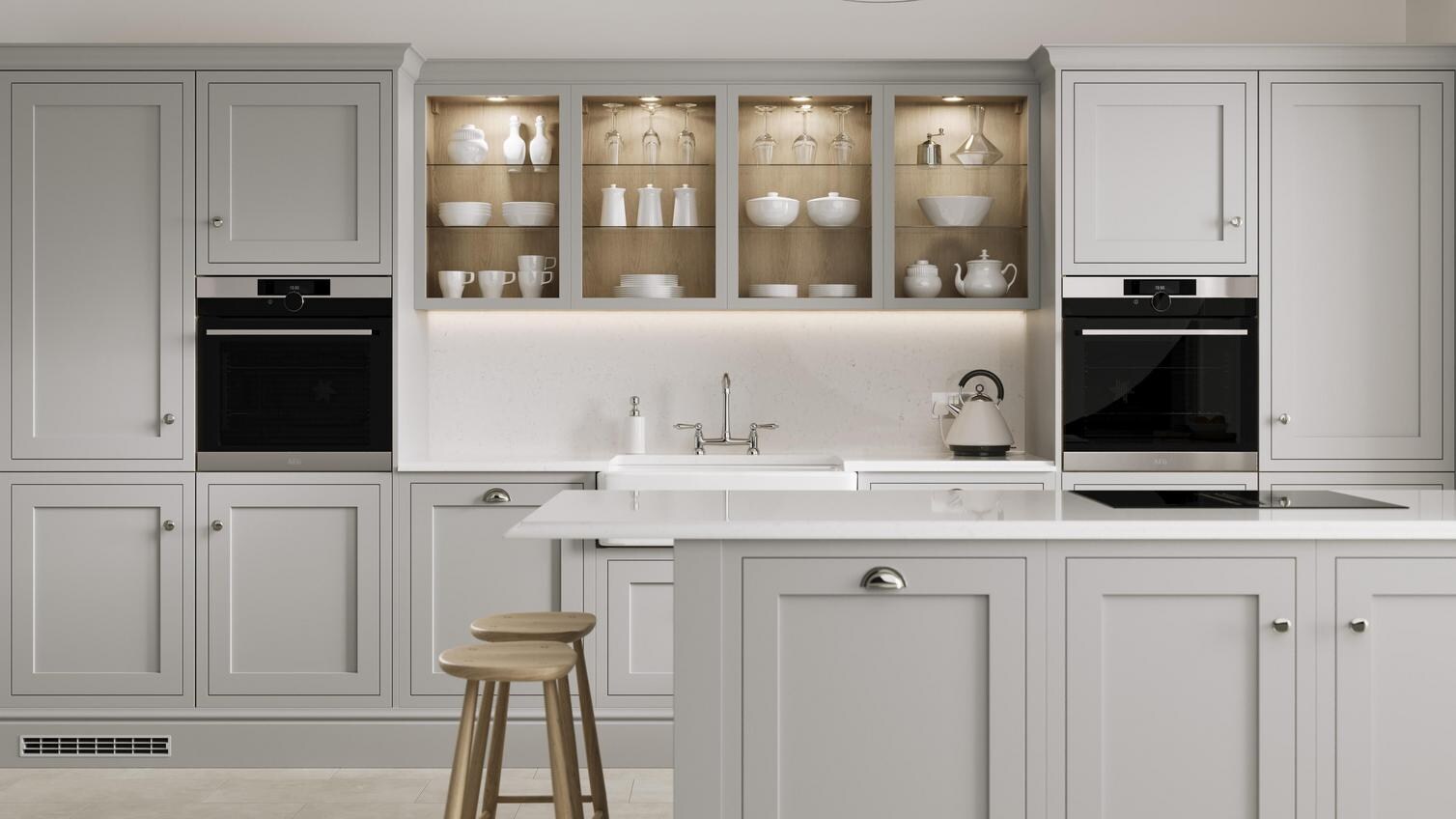 A dove grey shaker kitchen from Ilfracombe, in an island layout with breakfast bar. It has white counters and stone flooring