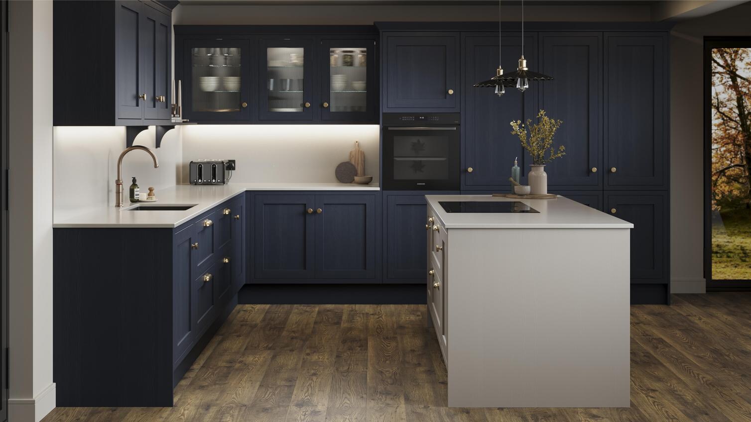 A navy shaker kitchen from Ilfracombe, in an l-shaped layout and a pebble-toned island. It also has dark oak flooring. 