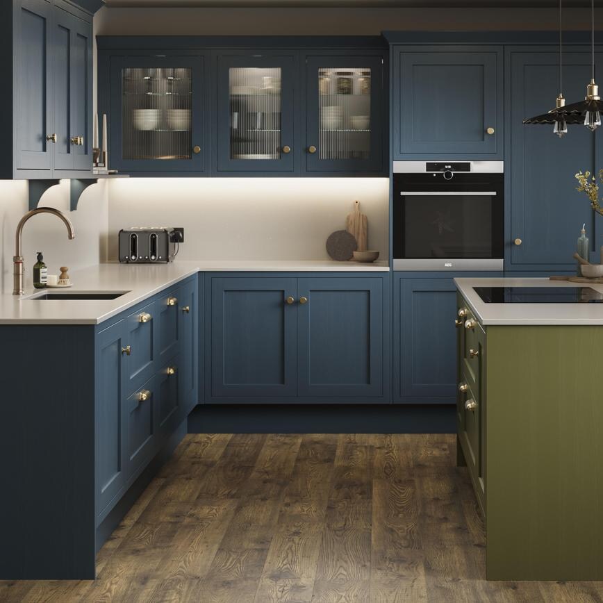 A marine blue shaker kitchen from Ilfracombe, in an l-shaped layout. It has an olive-colour island and oak plank flooring.