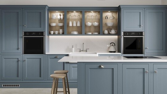A laguna blue shaker kitchen from Ilfracombe, in an island layout with breakfast bar. It has white counters and stone floors