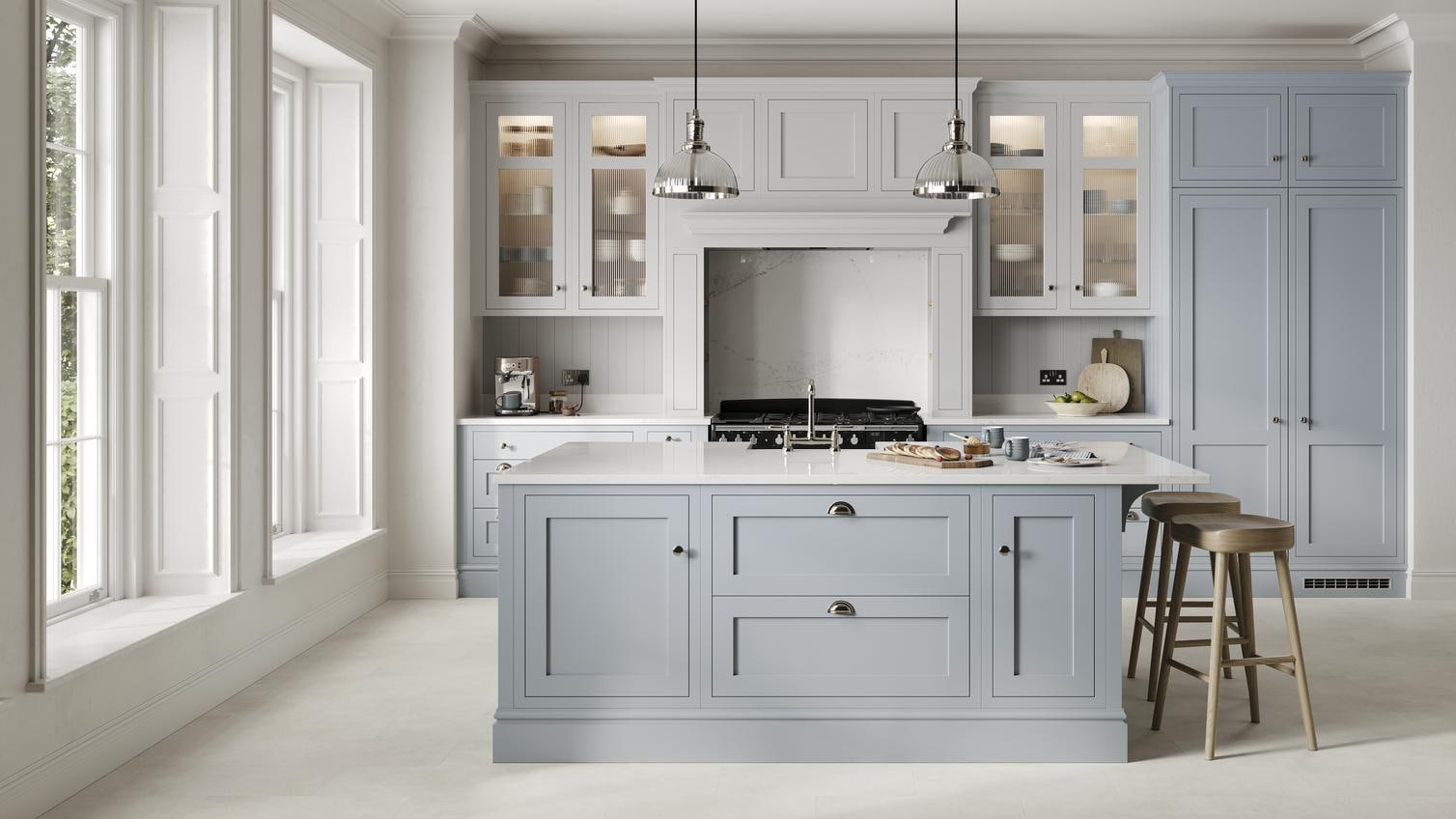 A mist blue, shaker Ilfracombe kitchen in an island layout. It has stone-effect flooring, marble effect breakfast bar. 