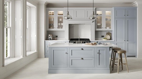A mist blue, shaker Ilfracombe kitchen in an island layout. It has stone-effect flooring, marble effect breakfast bar. 