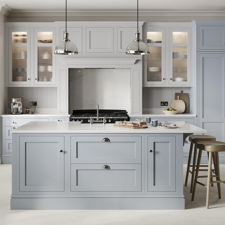 A mist blue, shaker Ilfracombe kitchen in an island layout. It has stone-effect flooring, marble effect breakfast bar. 