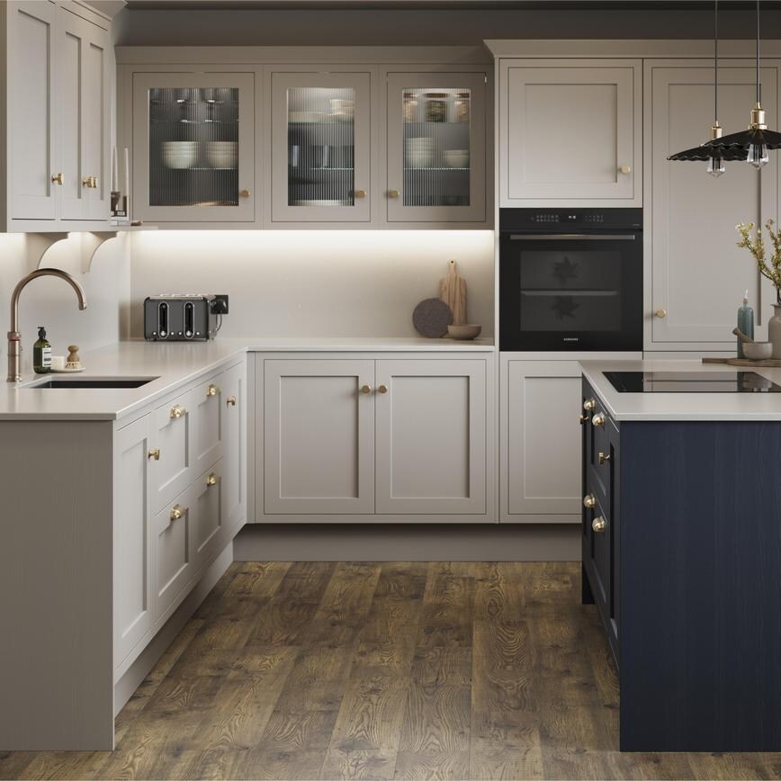 A pebble shaker kitchen from Ilfracombe, in an l-shaped layout and a navy-toned island. It also has dark oak flooring. 