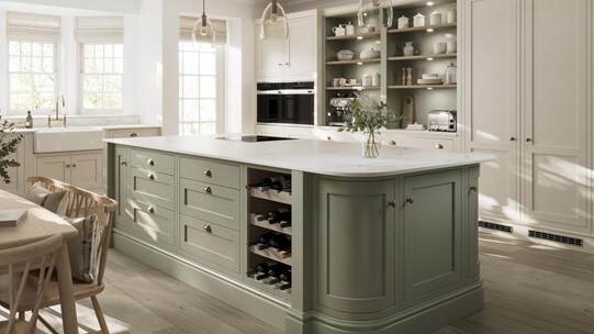 A sage green shaker kitchen from Ilfracombe, in a single wall layout. It has a sage green kitchen island and oak flooring. 