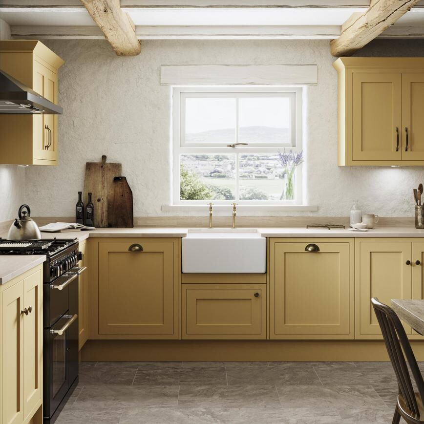 A yellow shaker kitchen from Ilfracombe Saffron, in an l-shaped layout. With wall cabinets, stone floors, and solid worktops