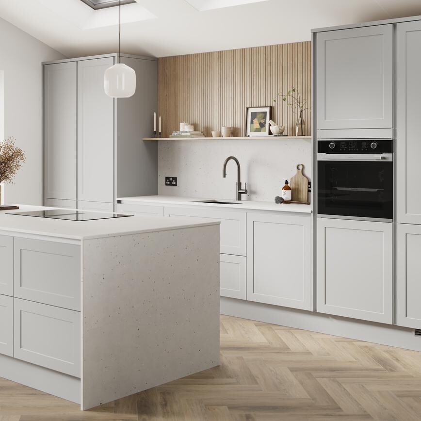 A dove grey, shaker kitchen island in a matt finish & handleless style. It has quartz worktops with side panels & backboard. 