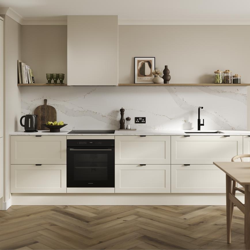 An l-shaped kitchen from Frome Porcelain, with shaker fronts in a matt finish. It has oak flooring & marble-effect worktops. 