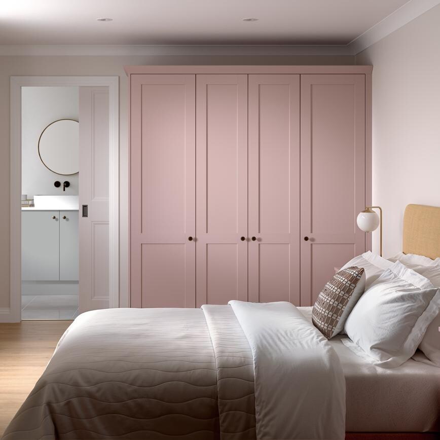 A Halesworth bedroom with pink, antique rose wardrobes & bedside table. It has oak flooring & pocket door to an en-suite.