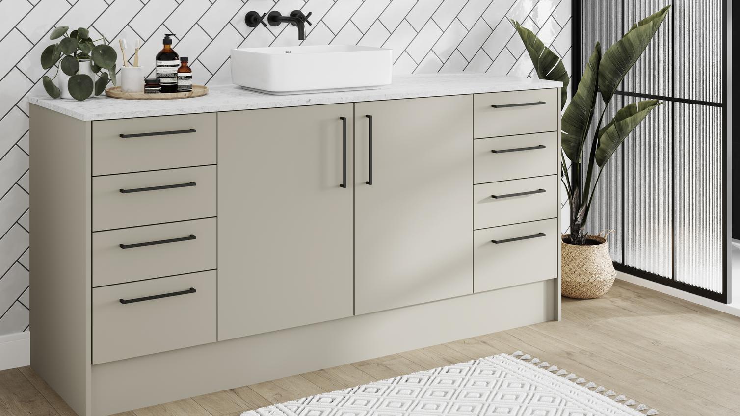 Slab bathroom with sandstone cupboard doors. Has a white worktop, tiles, oak floors, and black handles for a modern touch.